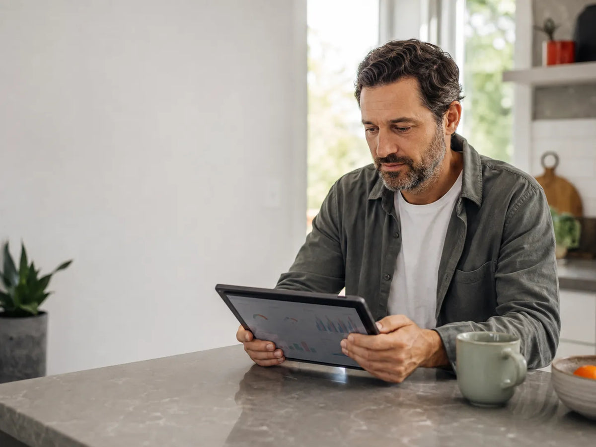 Man reviewing hormone lab results on a tablet in morning light