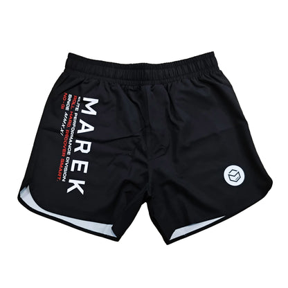 Black athletic training shorts with a white elastic waistband, featuring 'MAREK' printed vertically in white on the left leg, red text details, a white geometric logo on the right leg, and white piping along the hem.