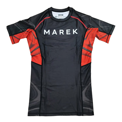 A short-sleeve athletic rash guard in black and red, featuring the brand name 'MAREK' printed in white across the chest, displayed flat against a white background.